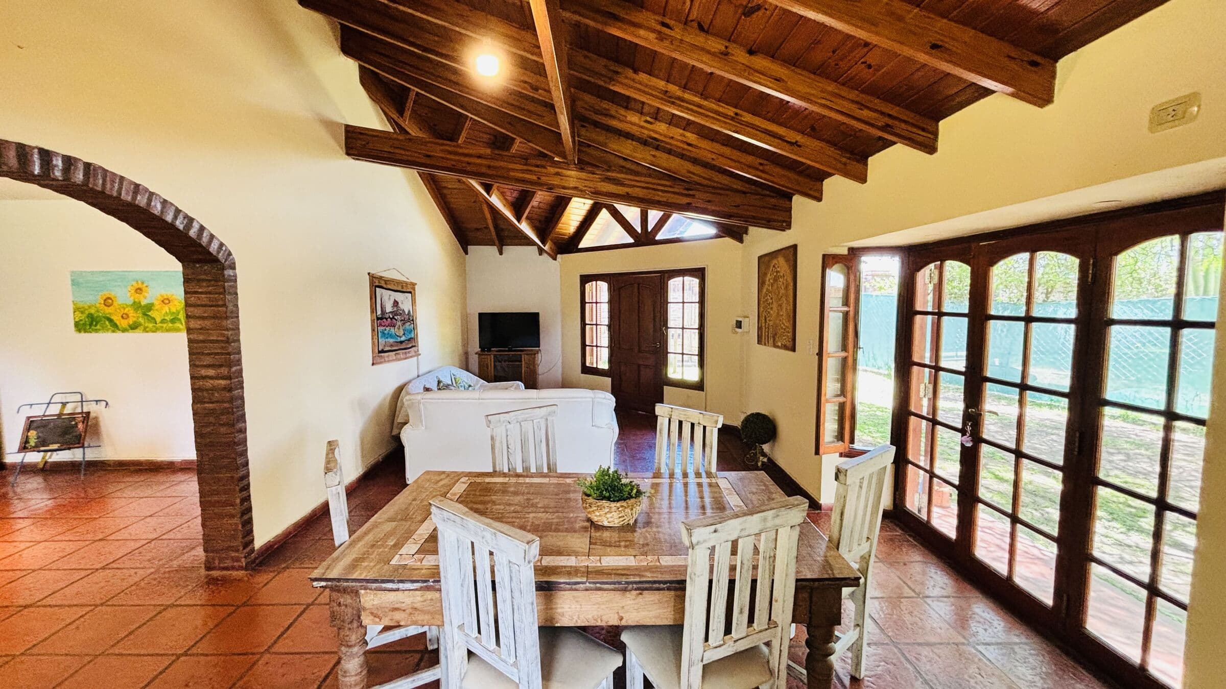 Living-comedor con techo de vigas de madera y puertas ventana