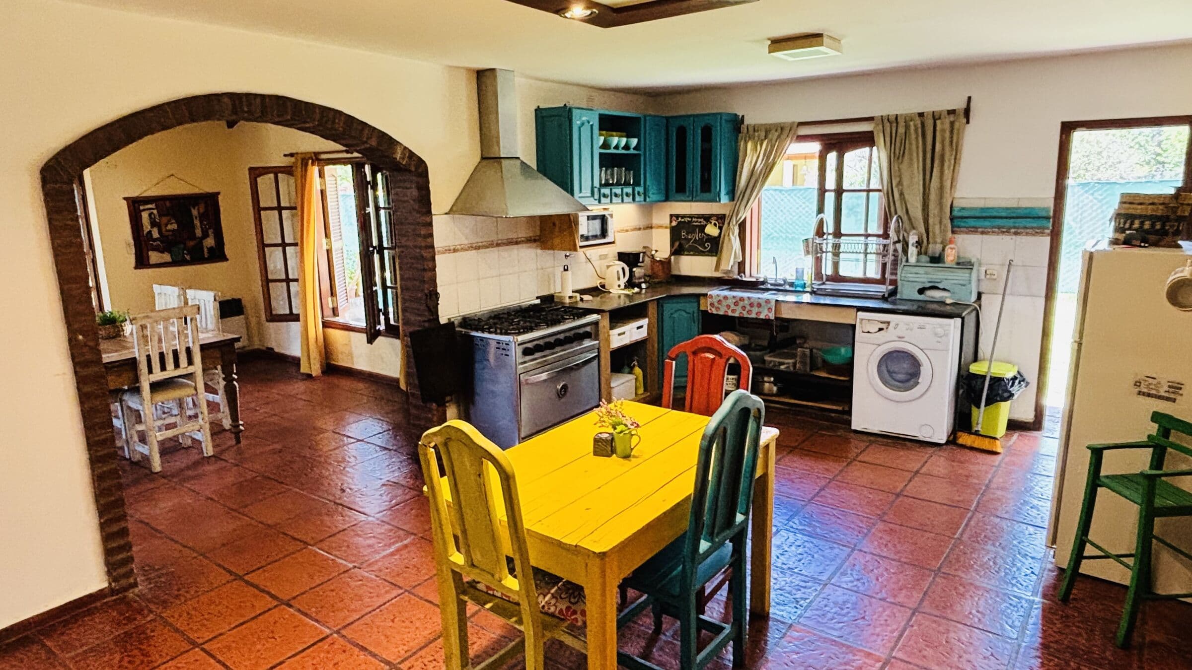 Cocina con alacenas turquesa, mesa amarilla y lavarropas
