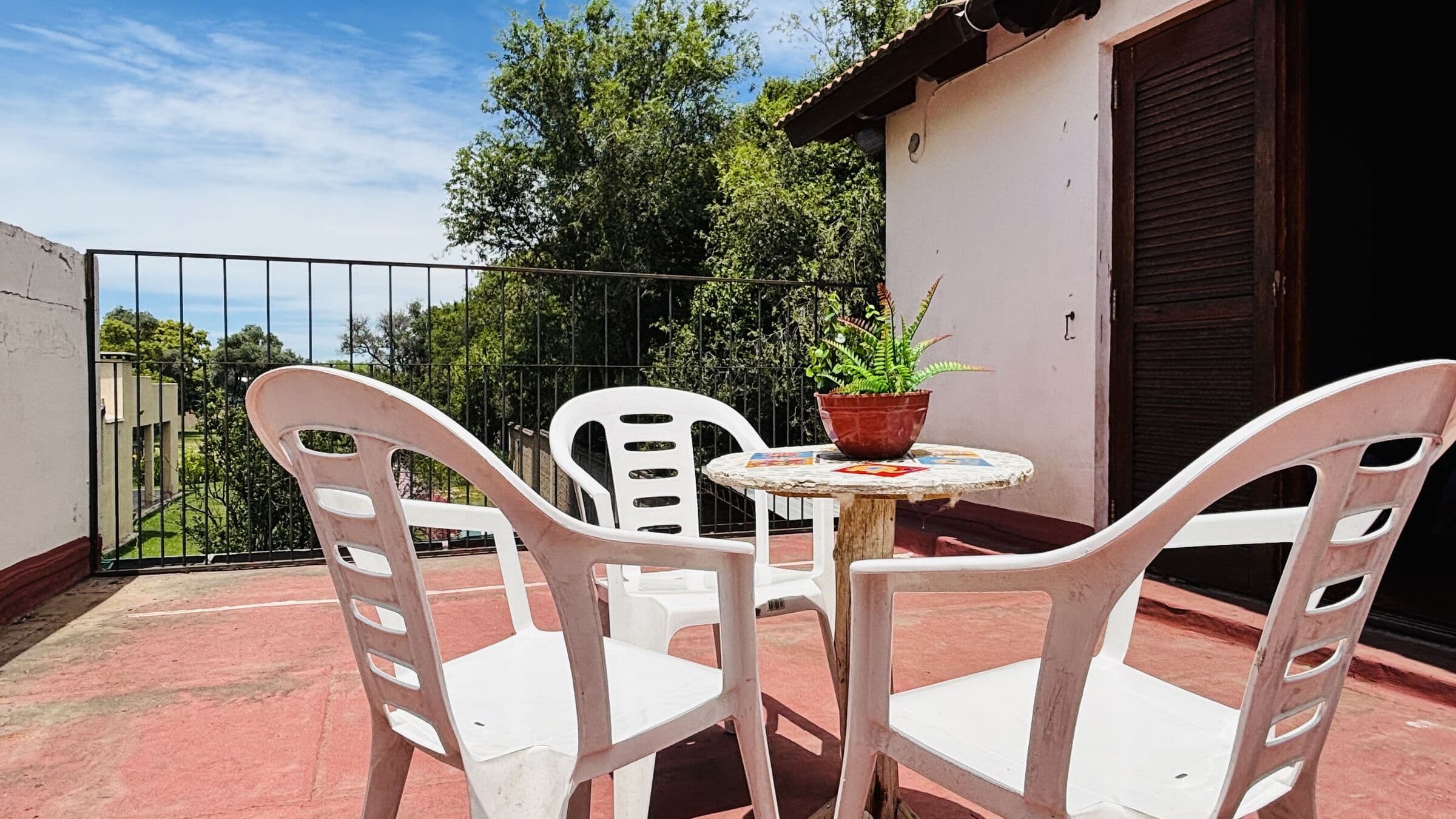 Terraza con mesa y sillas blancas rodeada de árboles